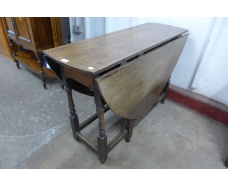A George II oak single drawer gateleg dining table and two chairs 