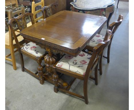An early 20th Century carved oak six piece dining suite, comprising; a draw-leaf table, four chairs and a sideboard 