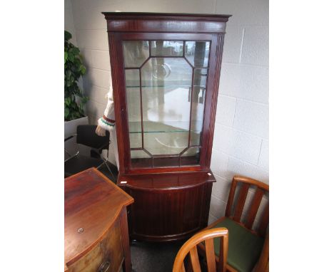 An early 20th century mahogany full height narrow display cabinet having glass top over bow cupboard base on slender tapered 