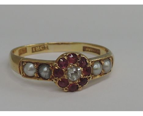 A ladies diamond and ruby cluster ring having seed pearl decoration to shoulders on a yellow metal loop stamped 18ct