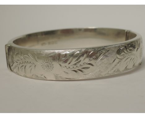 An HM silver hinged bangle having engraved decoration and inscription to reverse