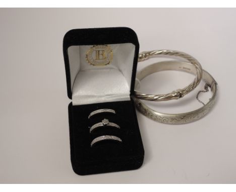 A trio of white metal and cubic zirconia rings stamped 925, a hinged HM silver bangle and a white metal hinged bangle having 