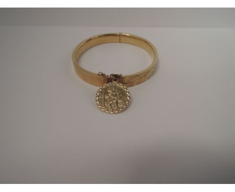 A 9ct gold hinged bangle having engraved decoration and St Christopher's medal,  approx 13.5g