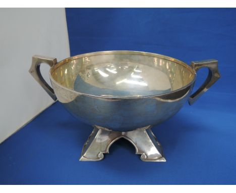 A silver punch bowl of Arts &amp; Crafts style having a moulded angular base with wrap over rim and architectural moulded han