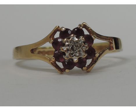 A ladies dress ring having a diamond chip and ruby cluster within open shoulders on a 9ct gold loop