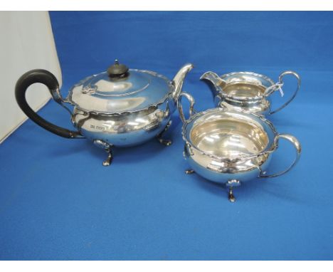 A three piece silver tea set of circular squat form on paw feet having hard wood knop and handle, Sheffield 1935, Walker & Ha