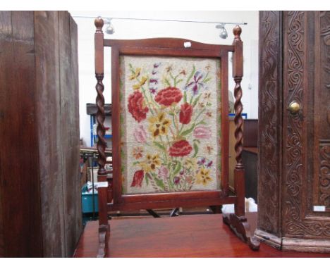 An early 20th century stained frame firescreen having inset floral woolwork panel