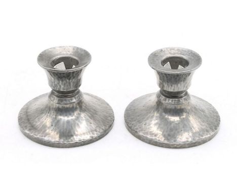 Tudric Pewter - A pair of early 20th Century Arts & Crafts hand hammered candle sticks, of small form with splayed feet. Each