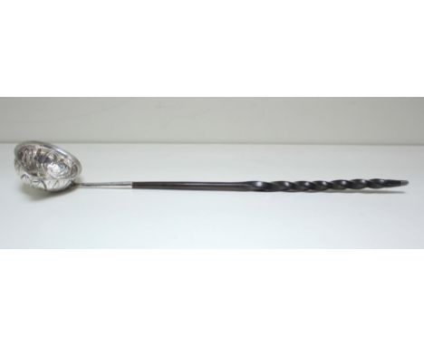 An early 19th century silver punch ladle, unmarked, the round bowl embossed and inset with a 1787 shilling coin, twisted whal