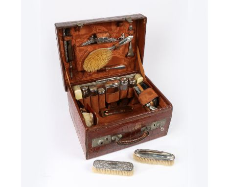 the brown crocodile skin case with watered silk lined fitted interior, containing various non-contemporary silver and plated 