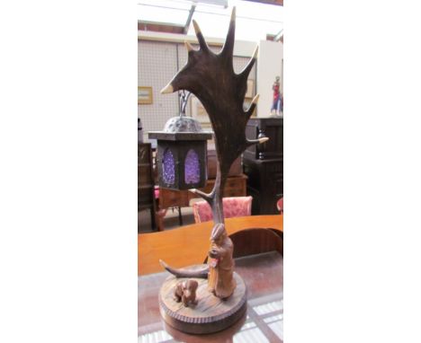 A continental moose antler table lamp with carved lamp lighter and dog