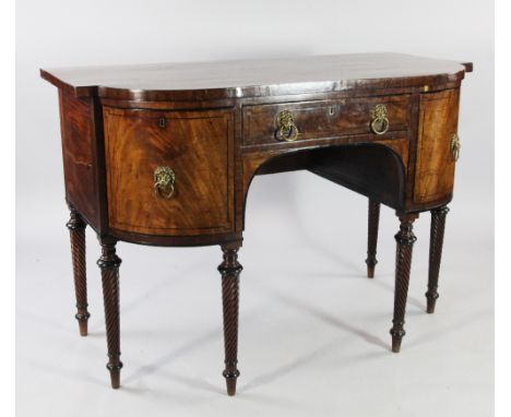 A Regency mahogany breakfront sideboard, with central frieze drawer between two bow end cupboard doors, with lion mask handle