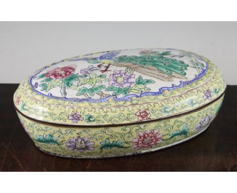 A Chinese enamel Canton enamel oval box and cover, late 19th / early 20th century, the cover painted with a peacock amid rock
