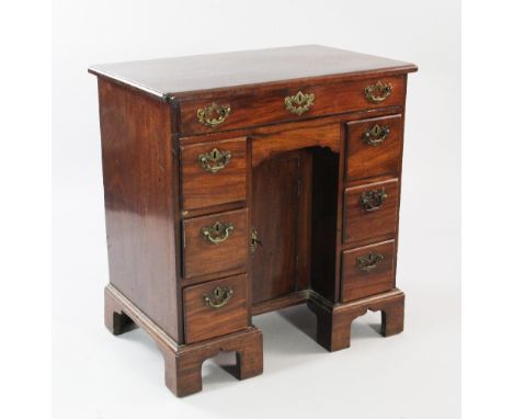 A mid 18th century mahogany kneehole desk, the moulded top with re-entrant corners, with central recessed cupboard door and a