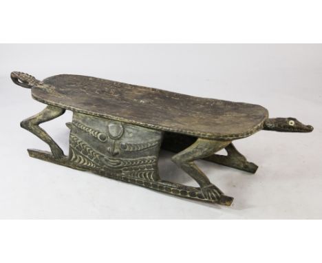 A Papua New Guinea Sepik River wooden ceremonial low table or bench, carved as a standing crocodile with looped tail and shel