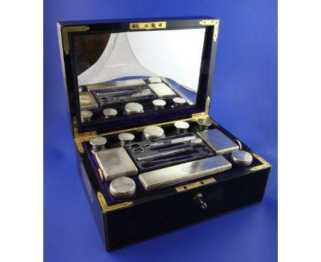 A Victorian brass mounted ebonised travelling fitted toilet box containing ten engine turned silver mounted jars, Adam Browne