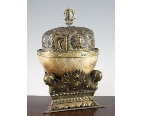 A Tibetan brass mounted human skull kapala, 19th century, the bowl with liner and the matching repousse work cover mounted wi