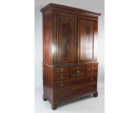 An early 19th century Scottish mahogany satinwood banded linen press, with two doors above central deep drawer and an arrange