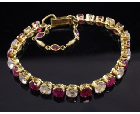 A Middle Eastern high carat gold, ruby and white topaz bracelet, set with twenty five alternating round cut stones, gross wei