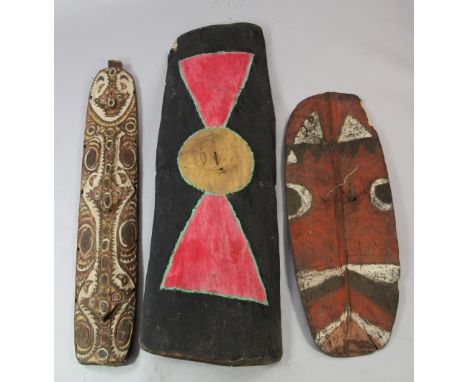 A Papua New Guinea Sepik River carved wooden shield, painted with a bold abstract design in white, ochre and red pigments; a 