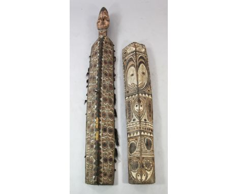 A Papua New Guinea Sepik River carved wooden shield, with human head finial inset with cowrie shell eyes and polychrome decor