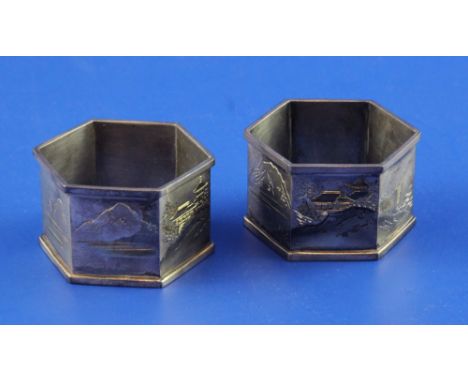A cased pair of Japanese silver hexagonal napkin rings, engraved with seascape and mountainous scenes, signed, 1.75in.