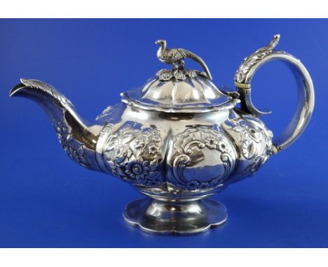 A William IV silver melon shaped teapot, embossed with flowers and scroll, on pedestal foot with pheasant finial, William Hew