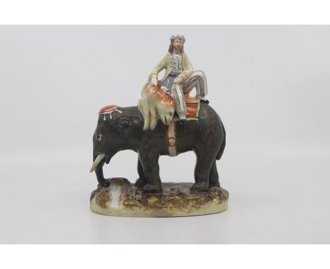 A Staffordshire figure group of a Mahout with slain tiger aboard an elephant, circa 1860, painted in colours and set on an ov