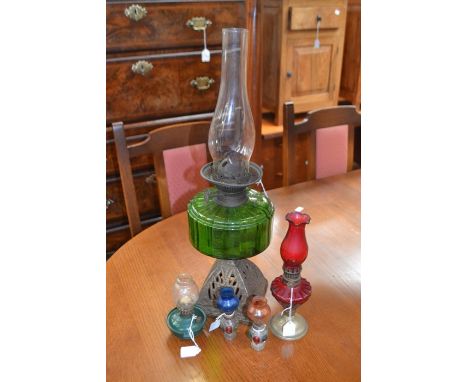A late 19th Century brass and green glass oil lamp, a small red coloured standing oil lamp, a further small oil lamp and a pa