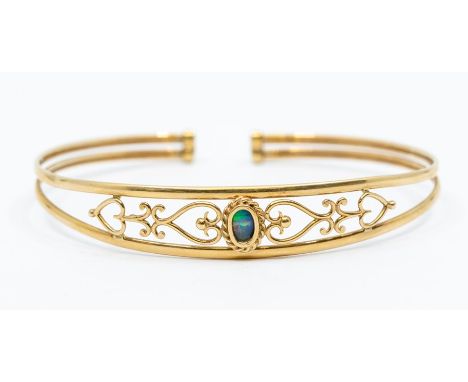 A yellow metal ladies bangle set with an opal to centre and a pierced surround, 5.06 grams approx