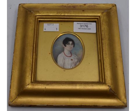 An early 19th Century portrait miniature depicting a young lady wearing a coral necklace and a coral brooch, fitted in a gilt