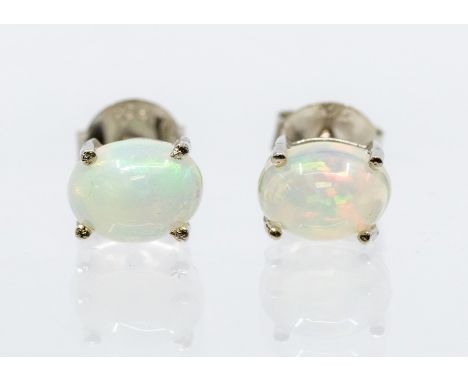 A pair of white opal and silver studs, oval opal set in four claw mounts, size approx  7 x 5mm, post and scroll fittings Cond