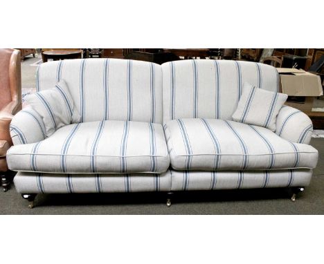 A 'Sofas &amp; Stuff' Four Seater Sofa with pale grey and blue striped upholstery, with bun feet and brass castors, approxima