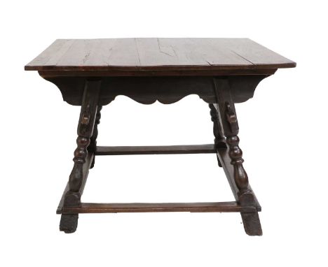 An 18th Century Continental Oak Dining Table, the plank top formerly with drawer leaves above a wavy shaped apron and arched 