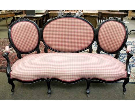 A Victorian Ebonised Sofa, with floral carved oval back rests and on scroll supports, in check upholstery, approximately 188c