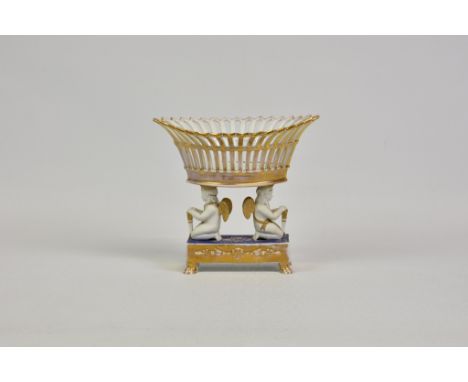 A pierced and gilded porcelain navette shape basket with everted sides, supported by two kneeling putti on a rectangular step