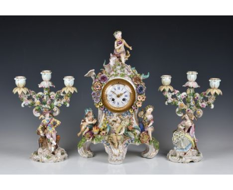 A Meissen style mantel clock garniture the clock with applied putti and flowers, 19in. (48.2cm.) high, with a pair of matchin