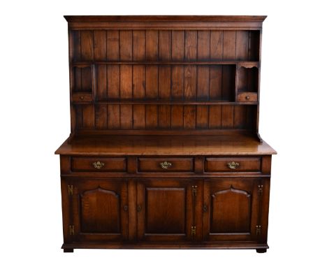 A George III style oak dresser late 20th century, the moulded cornice over an enclosed plate rack with two shelves and two sm