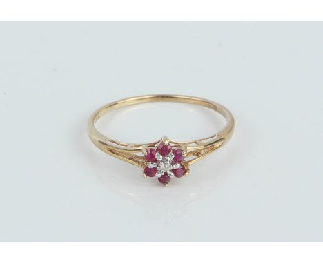 A dainty 9ct gold, diamond and ruby daisy cluster ring - etched '375' marks, with pierced shoulders, size O.