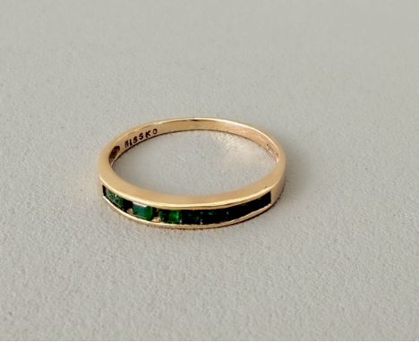 A 10ct yellow gold and emerald half-eternity ring - stamped '10K', size M. (one stone missing)