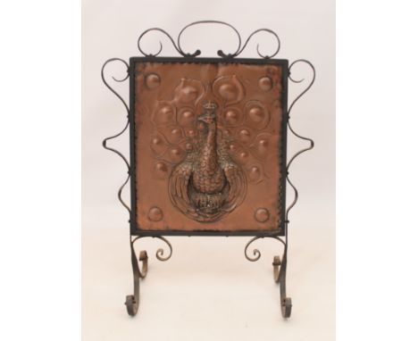 An Arts and Craft style copper and wrought iron fireguard - the copper panel decorated with a peacock. (LWH 59 x 31.5 x 78cm)
