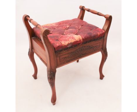 An Edwardian carved mahogany piano stool - the hinged buttoned red leather seat (worn) between two turned handles, the front 