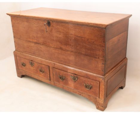 An 18th century mid-oak mule chest - the hinged top with original lock and key, over a plain front, the slightly outset base 
