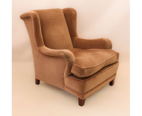 A vintage wingback armchair - upholstered in pale-brown velour with loose feather seat cushion, raised on stained square tape