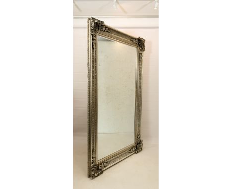 A large silvered gilt antique-style mirror - late 20th century, the bevelled plate within a fluted hollow frame with bold she