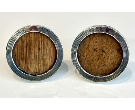 A pair of Edwardian silver circular photo frames - Birmingham 1906, with oak easel backs and engine turned and chased foliate