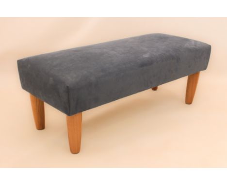 A modern ottoman or footstool upholstered in blue Alcantara fabric - on turned light wood supports. (LWH 106 x 45 x 41cm)
