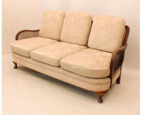 A three-seater beech and walnut berg&egrave;re-style settee, 1920s-30s - the three-panel caned back with stylised foliate cre