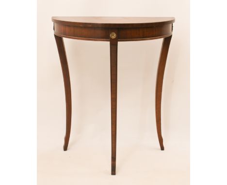 A small reproduction mahogany demilune side table - the cross-banded top raised on three sabre supports headed by brass flora
