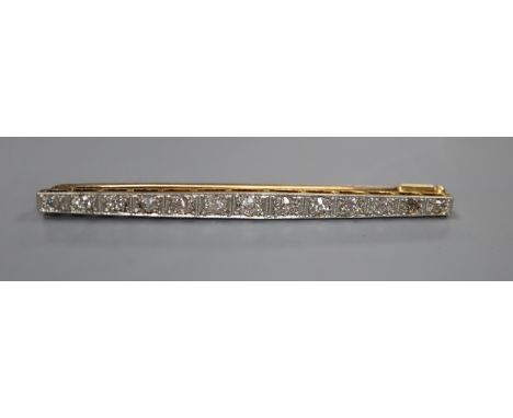 An early 20th century 15ct, plat and graduated thirteen stone diamond set bar brooch, 57mm, gross 4.7 grams.CONDITION: One of